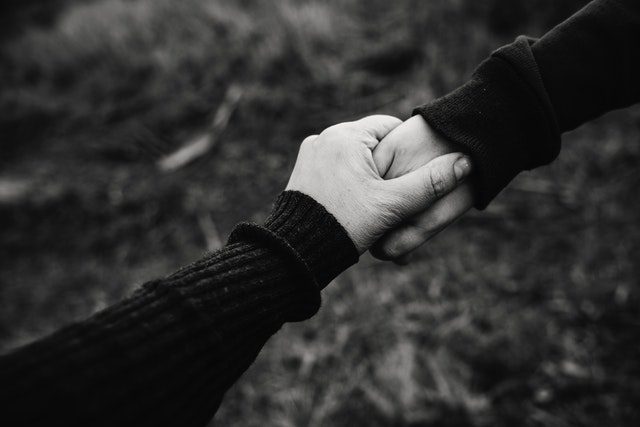 Two individuals joining hands
